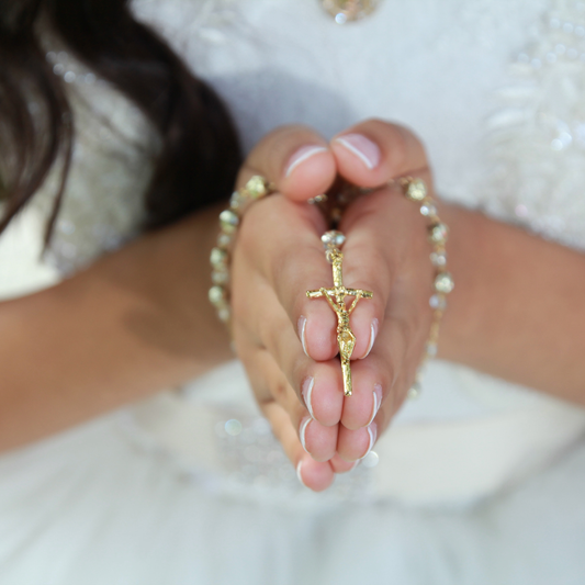 Mains d'enfant tenant un chapelet le jour de sa première communion